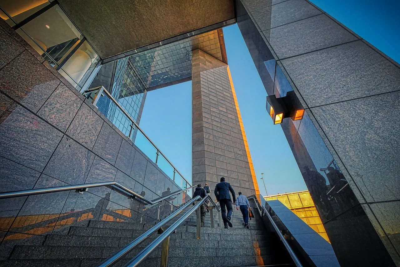 People walking up steps through modern business-district architecture
