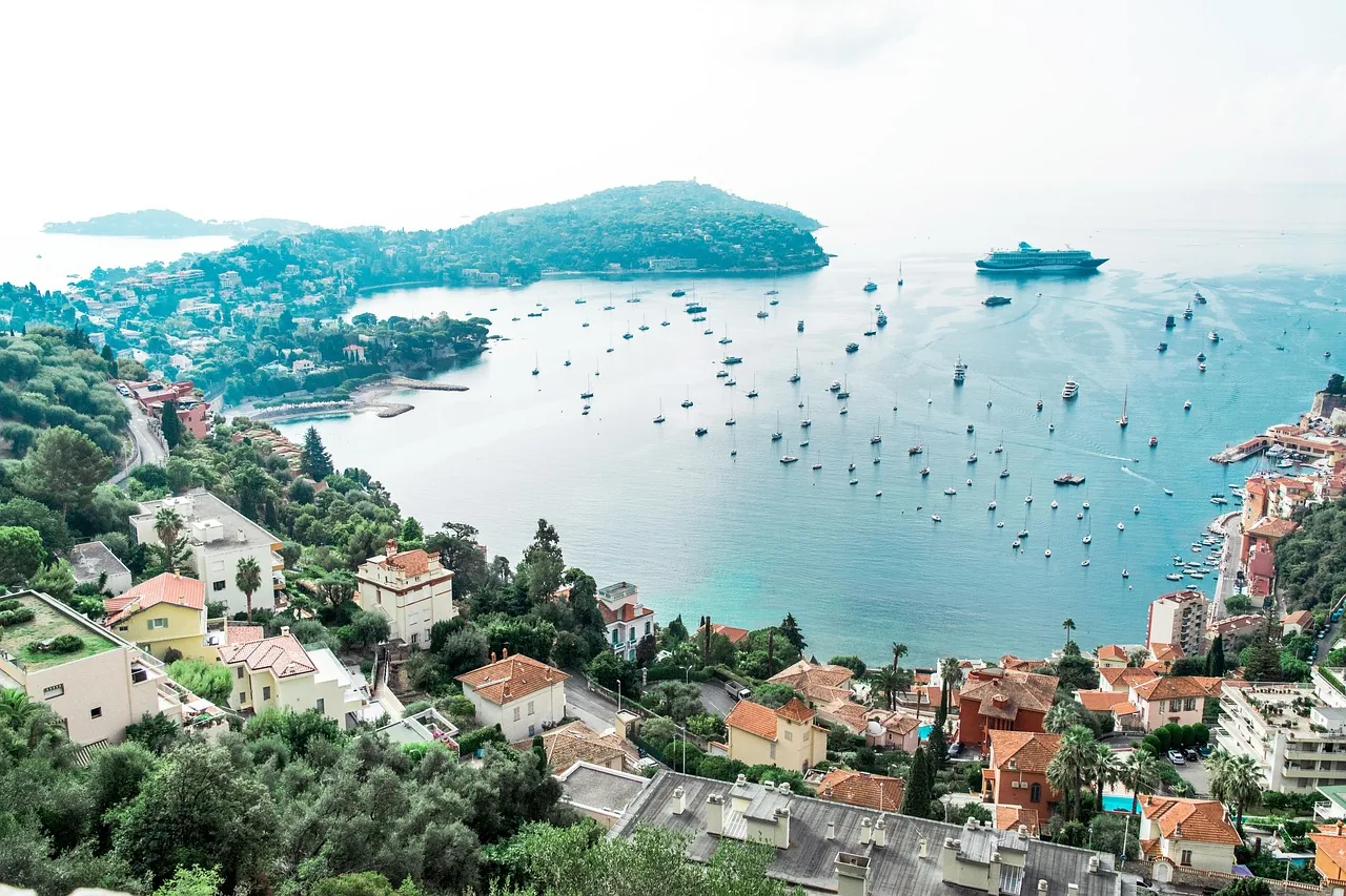 Coastal bay with boats, waterfront buildings and a cruise ship offshore