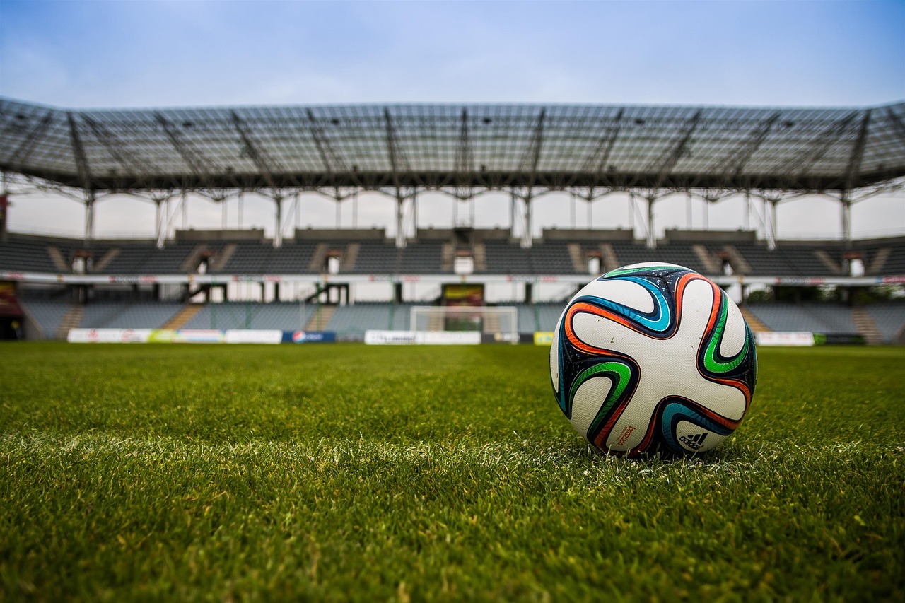Soccer ball on grass in front of stadium seating
