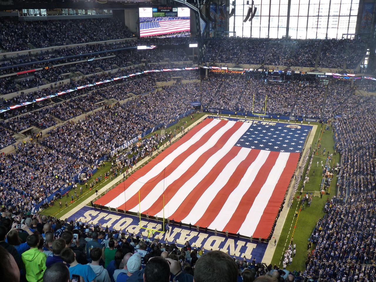 Football field and spectators at Lucas Oil Stadium with a large American flag