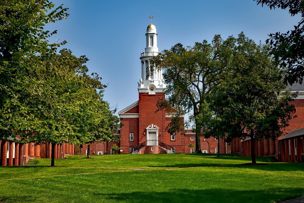 A university courtyard with green lawns, red-brick buildings and a white steeple